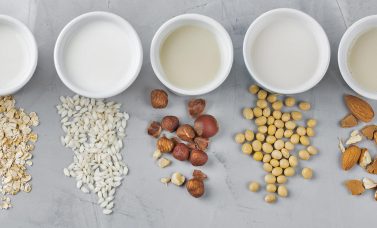 Flat lay at Non-dairy alternatives Soy milk or yogurt in mason jar and tofu on white wooden table with soybeans in bowl aside
