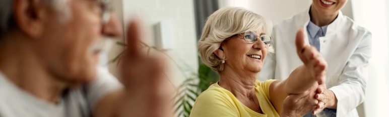 Happy physiotherapist helping to senior couple with stretching e